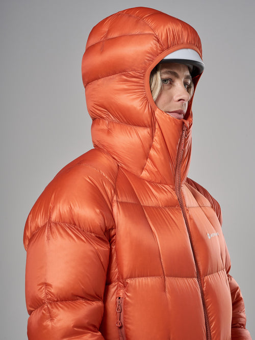 Person wearing an orange puffer jacket on a gray background